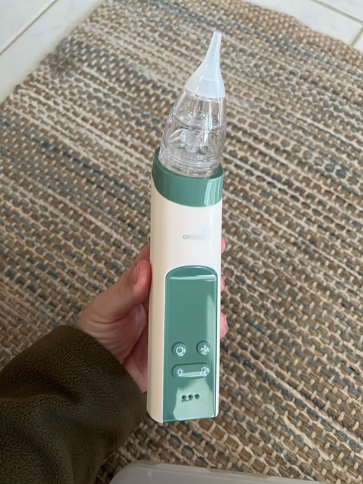 Hand holding the Graco Nasal Aspirator, an physics  instrumentality  designed for safely clearing a baby's nasal passages