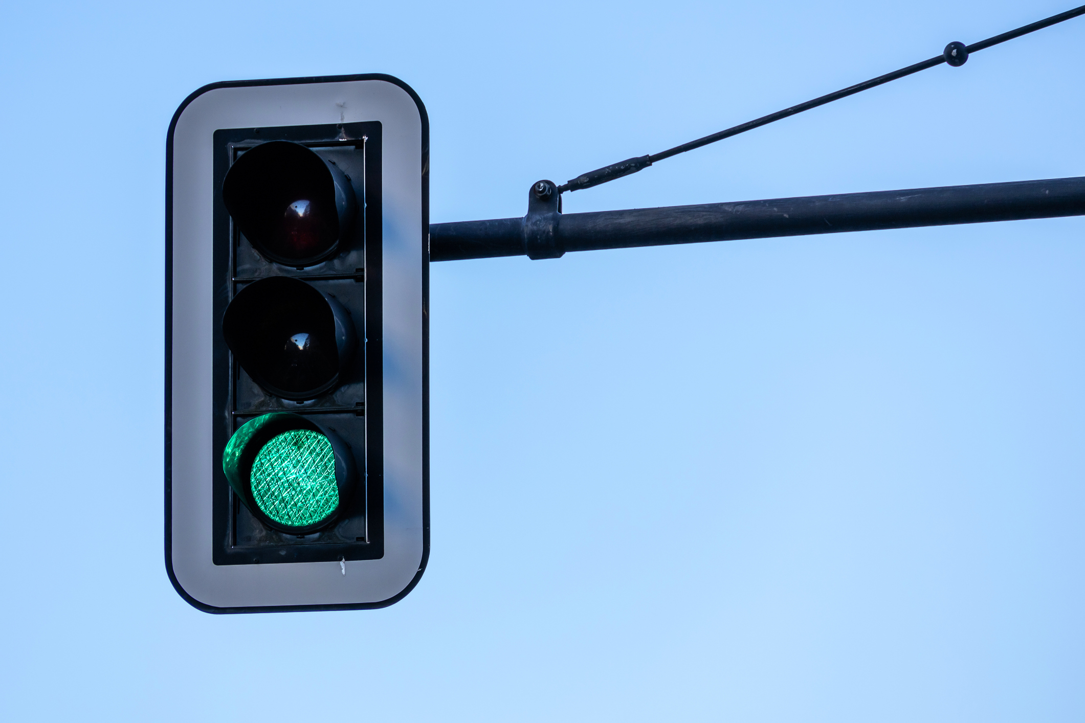 A traffic light with a lit green signal against a clear sky