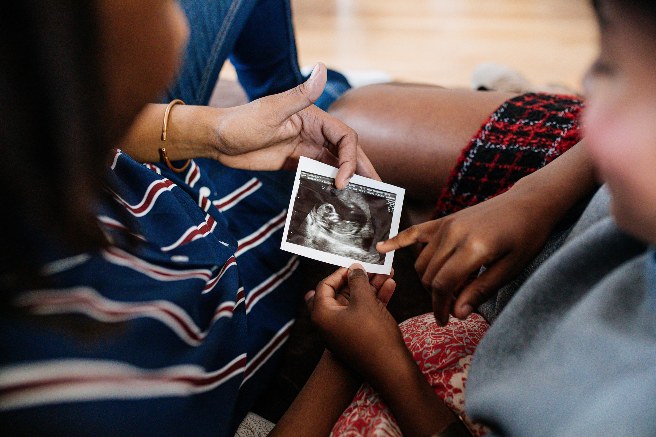 A person shows an ultrasound image to two children who point at it