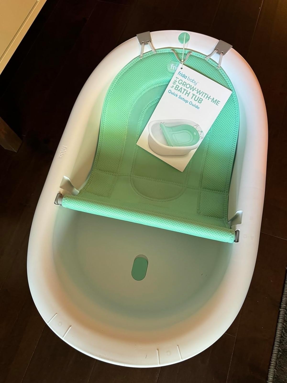 Frida Baby 4-in-1 Sling 'n Seat Bath Tub with a greenish  mesh enactment    sling, showcasing the merchandise  and its Quick Setup Guide