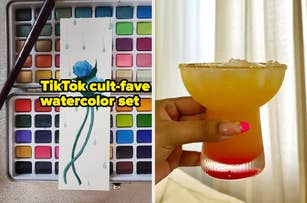 A TikTok cult-fave watercolor set with a blue flower painting on the left; on the right, a hand holding a yellow and red drink in a glass with a salted rim
