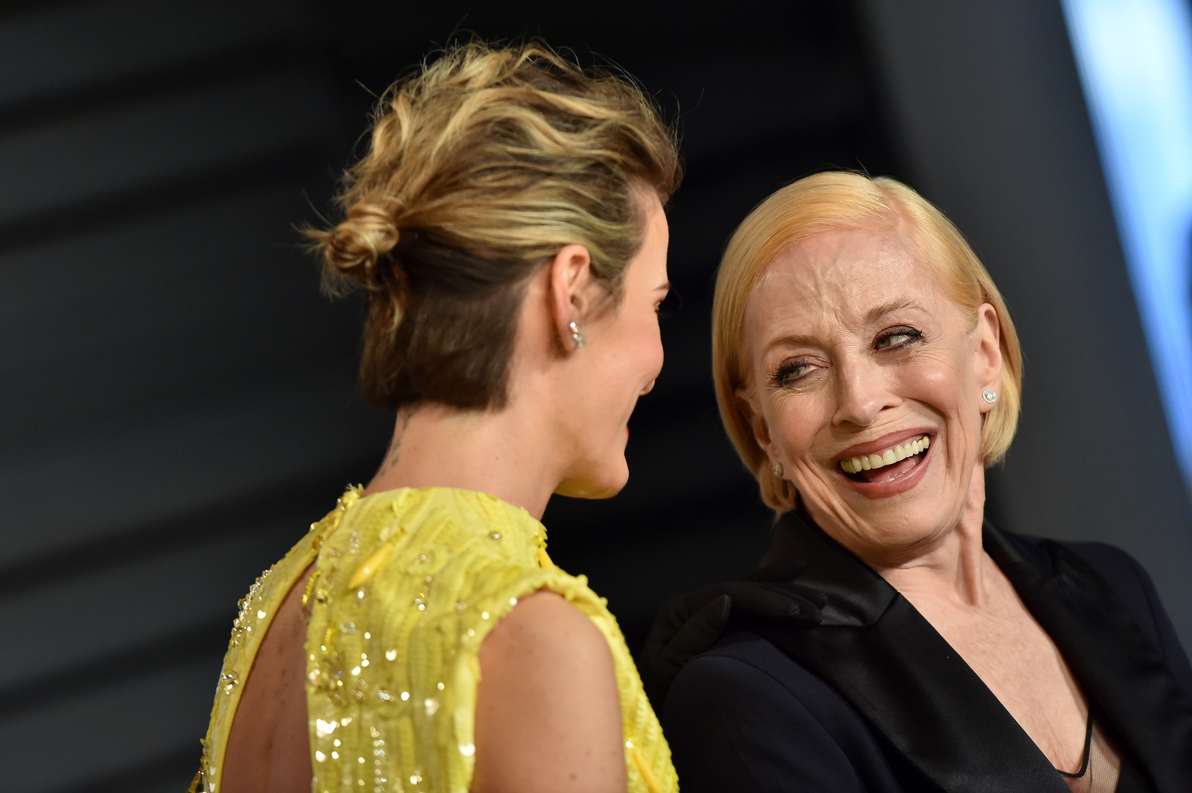Sarah Paulson, in a sequined dress, and Holland Taylor, in a dark outfit, smiling and conversing at an event