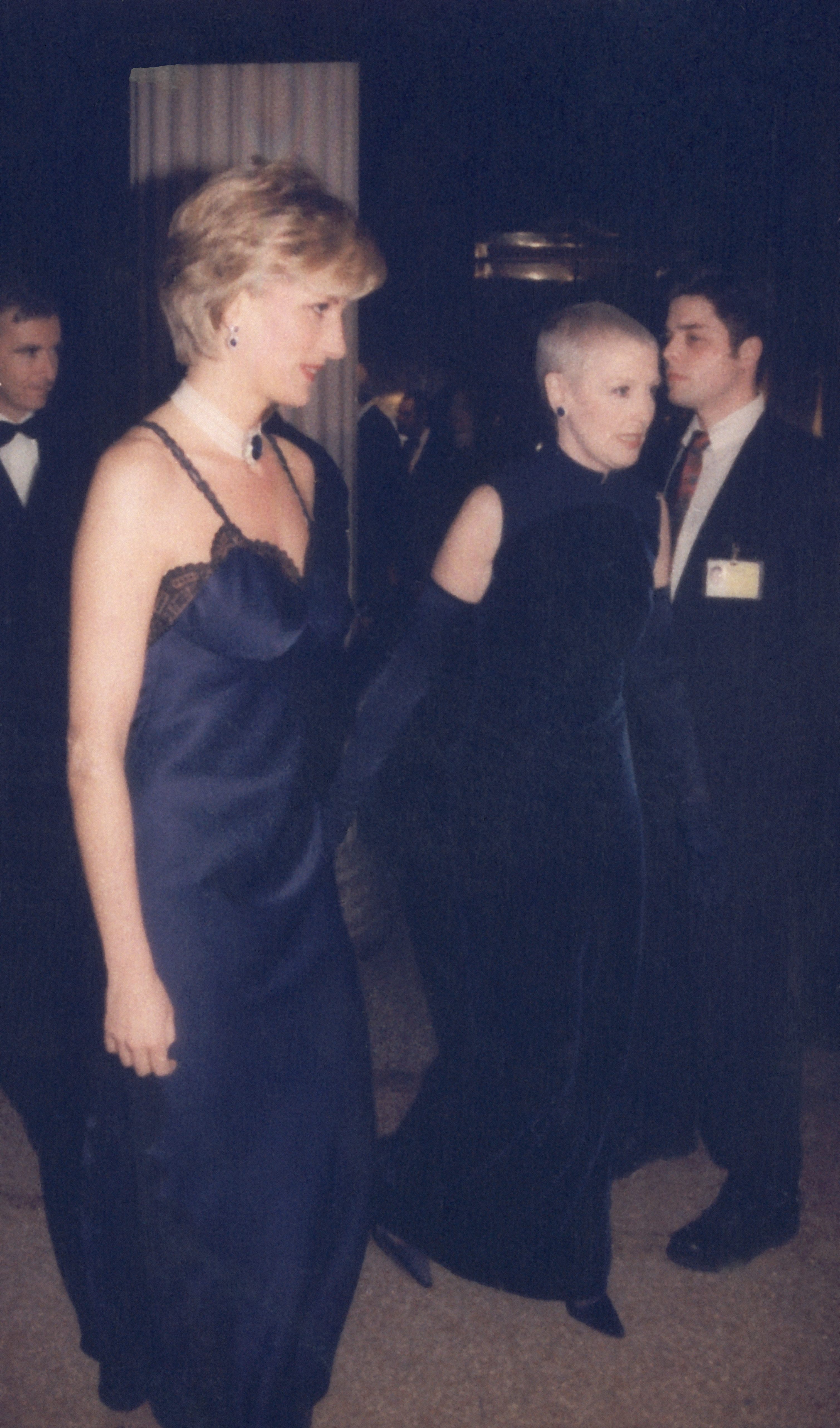 Princess Diana, Jean Louis Scherrer, and two unidentified people at an event. Diana and Scherrer are wearing elegant evening gowns