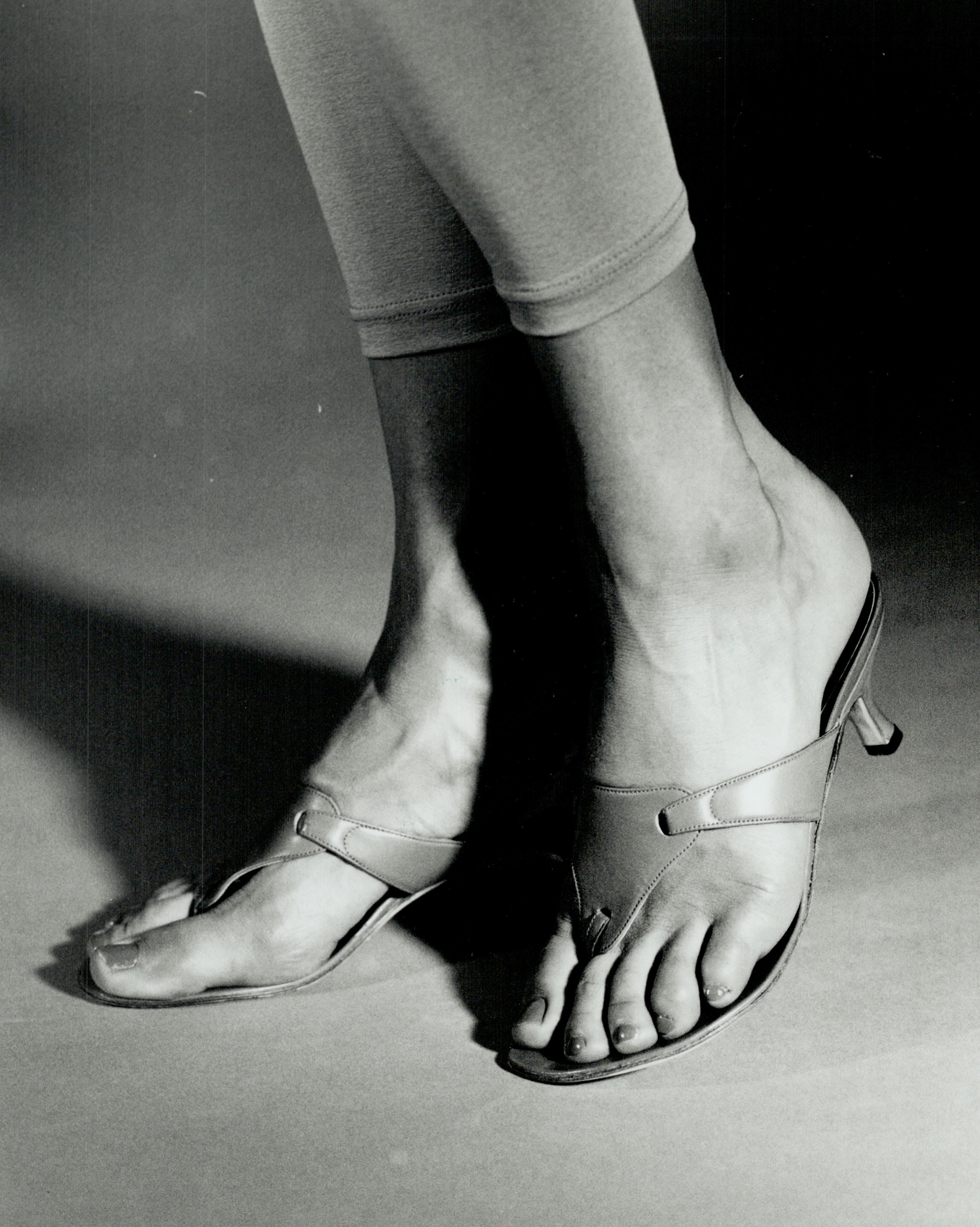 Person wearing open-toed, slip-on heeled sandals and leggings, showing a unique footwear style