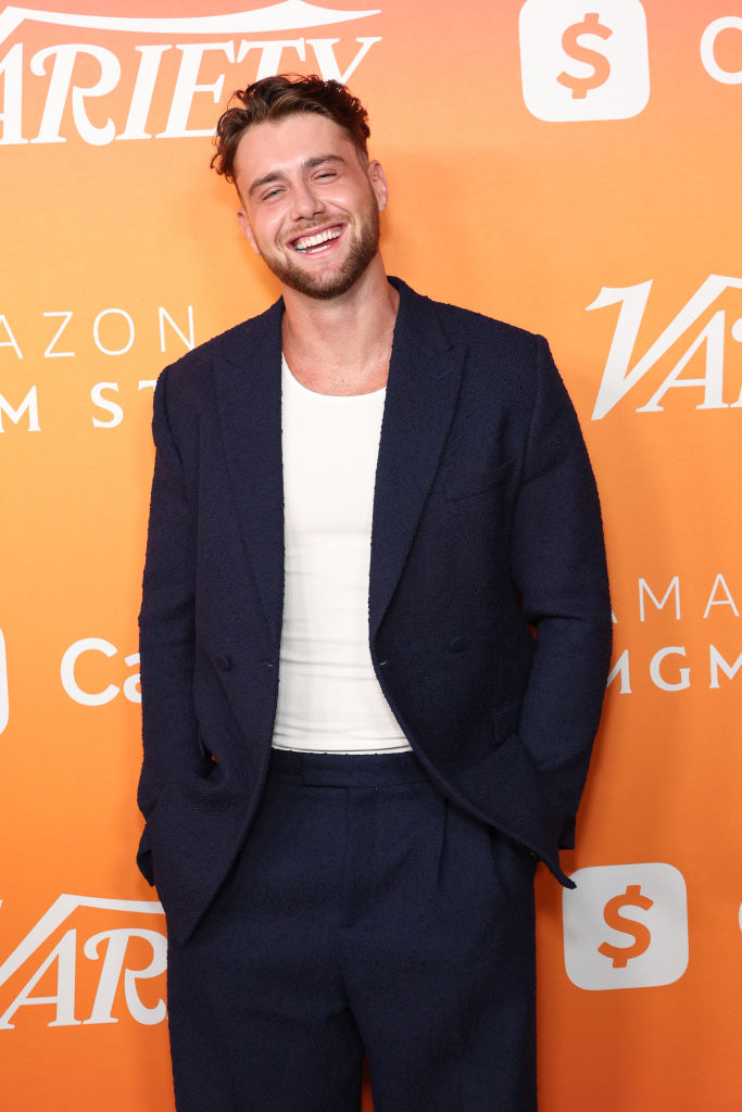 Harry Jowsey smiles in a casual white shirt and dark suit on the red carpet at a Variety event
