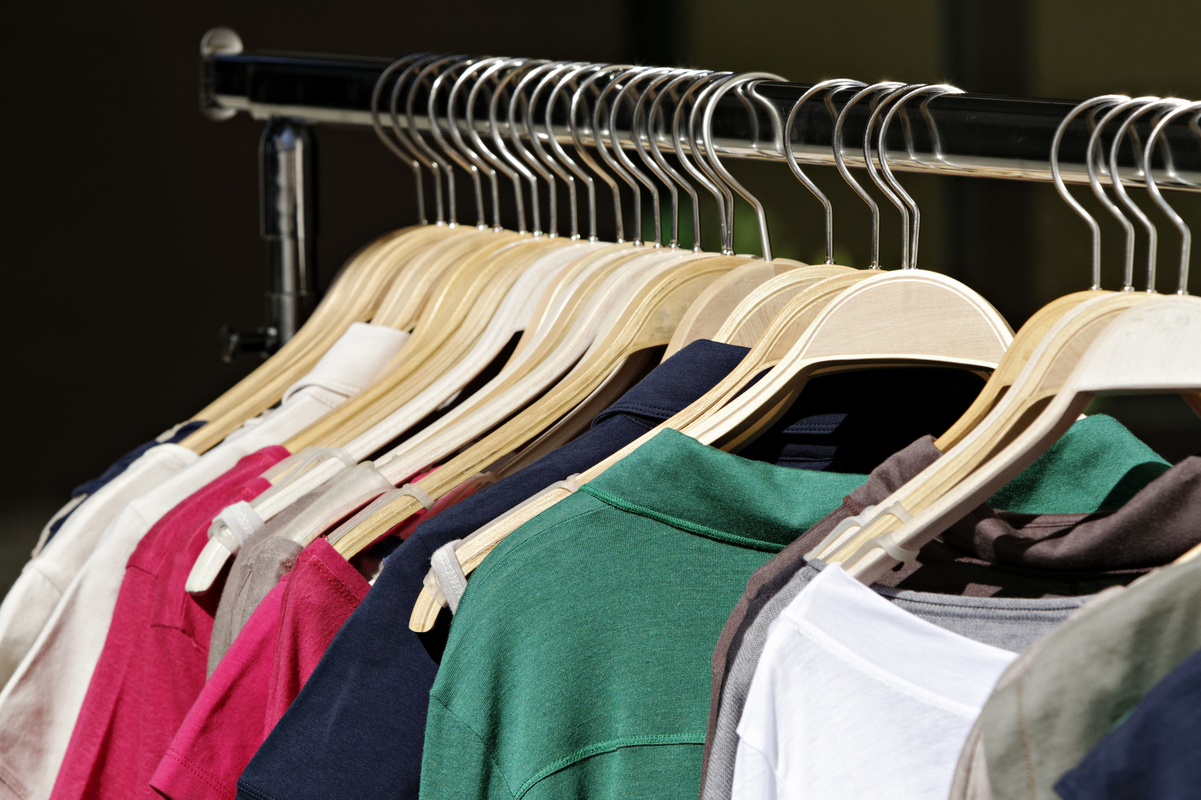 Close-up of various clothing items, including shirts and jackets, hanging on a garment rack