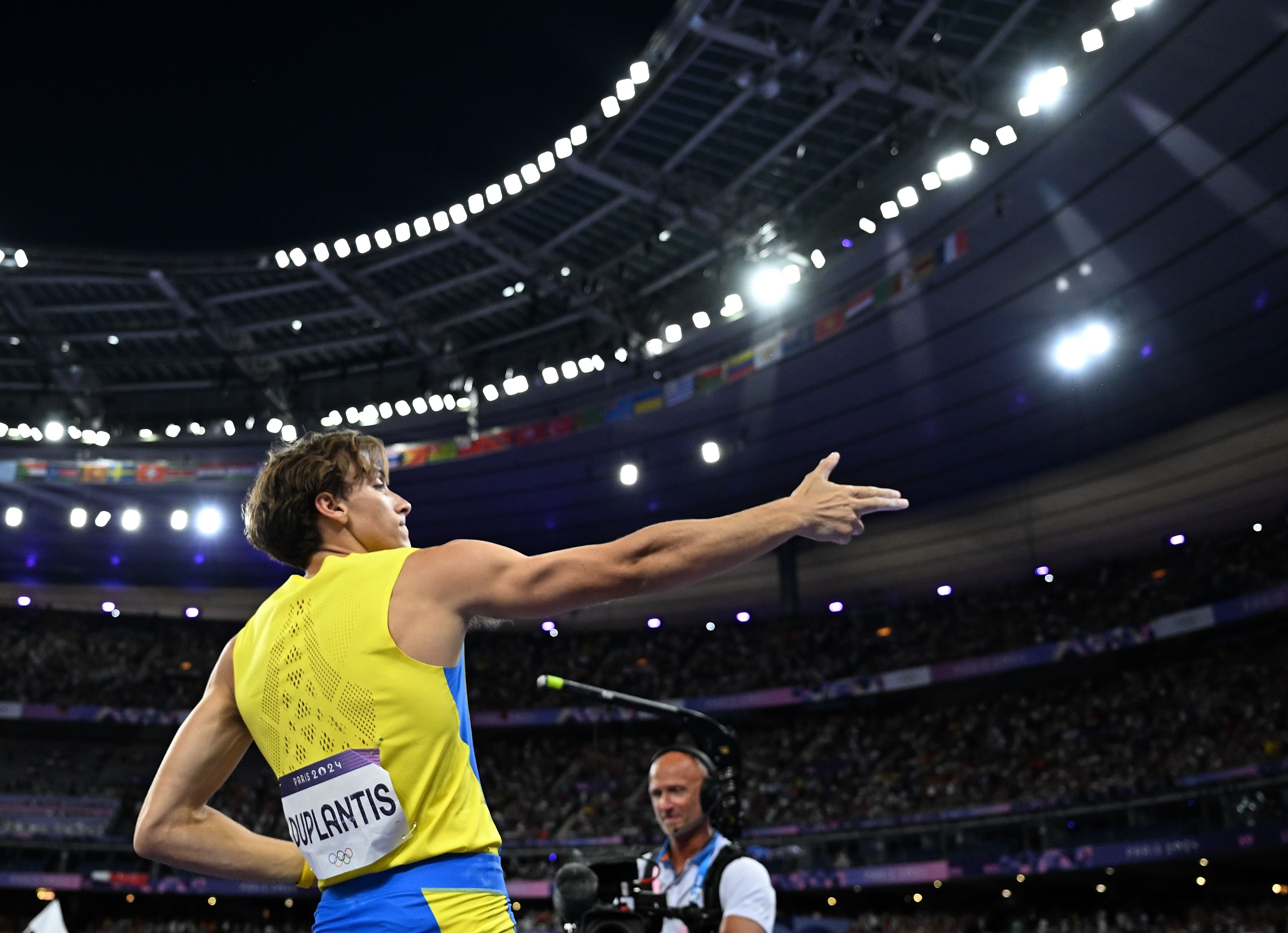 Athlete Armand Duplantis points while competing in a stadium during a track and field event