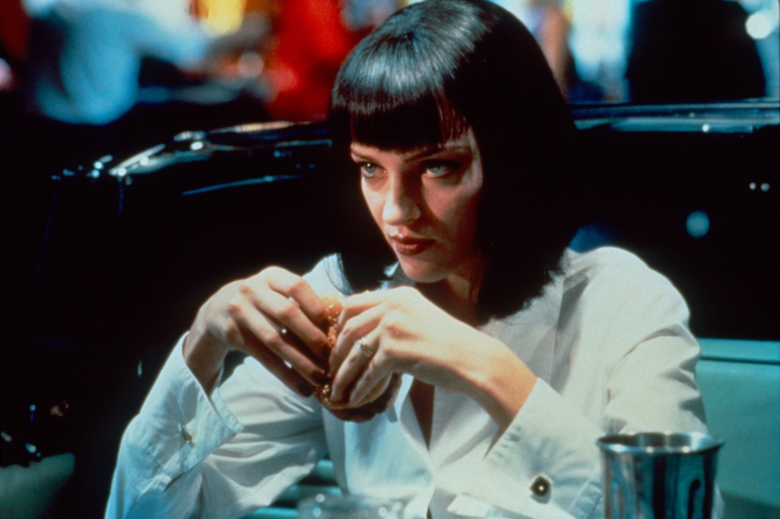 Uma Thurman with short dark hair and a button-up shirt in a scene from "Pulp Fiction"