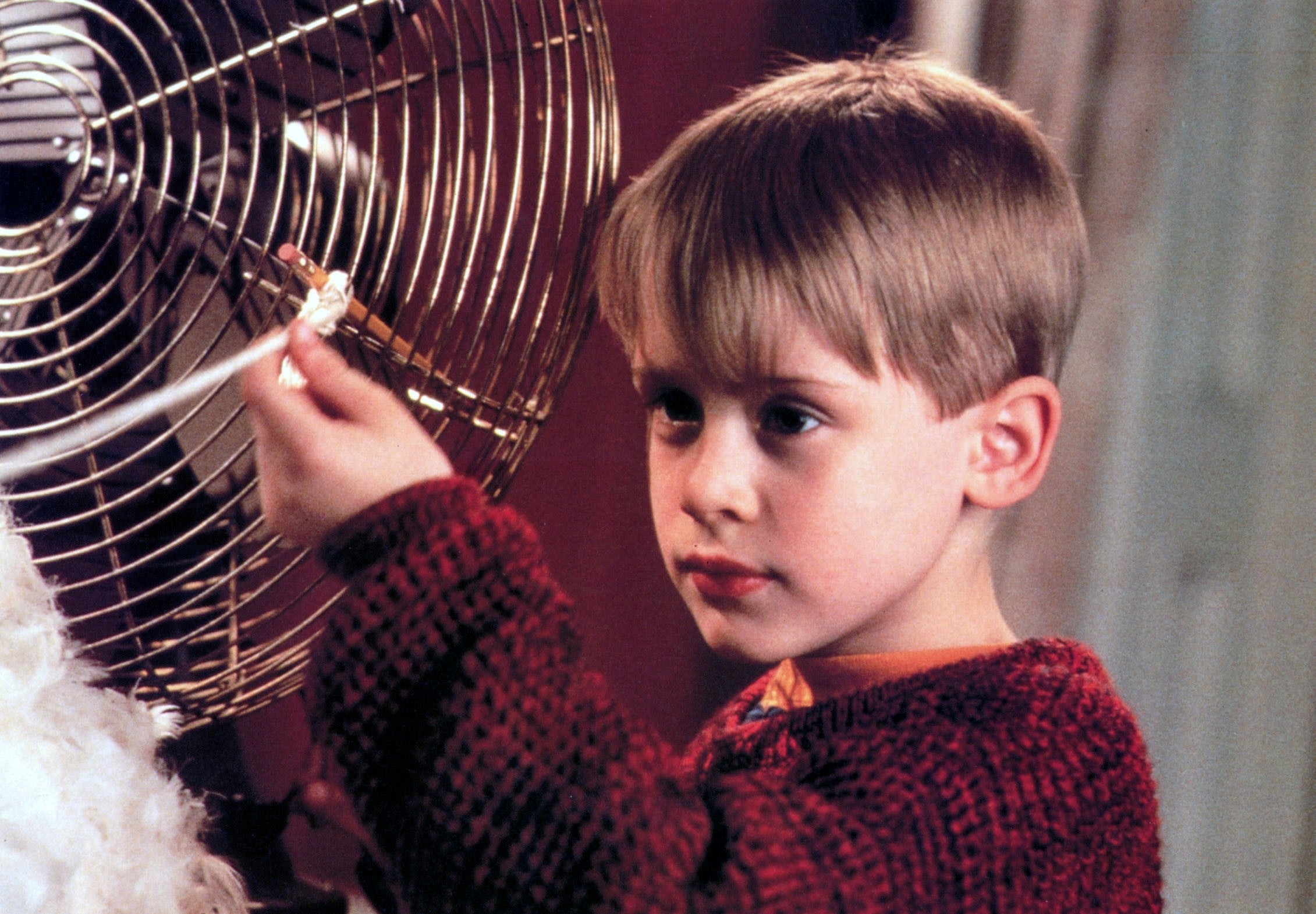 Macaulay Culkin standing by a fan in a scene from "Home Alone"