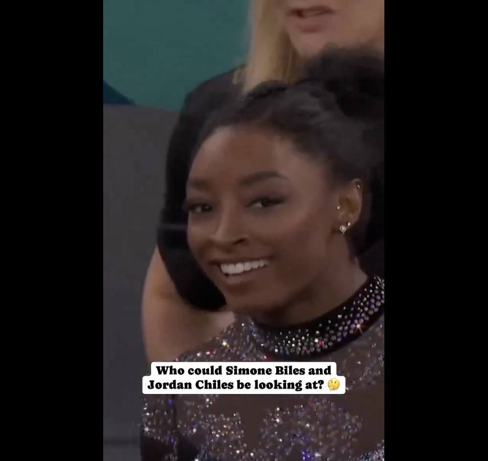 Simone Biles smiles, Text on the image asks, "Who could Simone Biles and Jordan Chiles be looking at?"