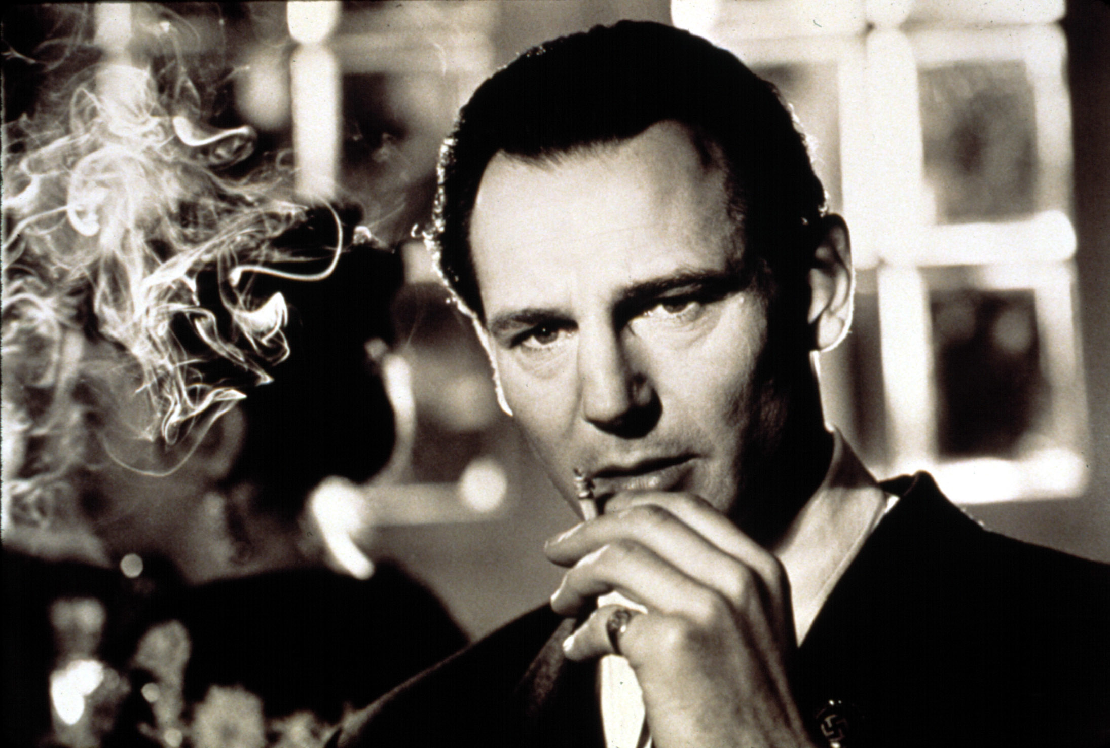 Liam Neeson smoking in a black-and-white scene from "Schindler's List"
