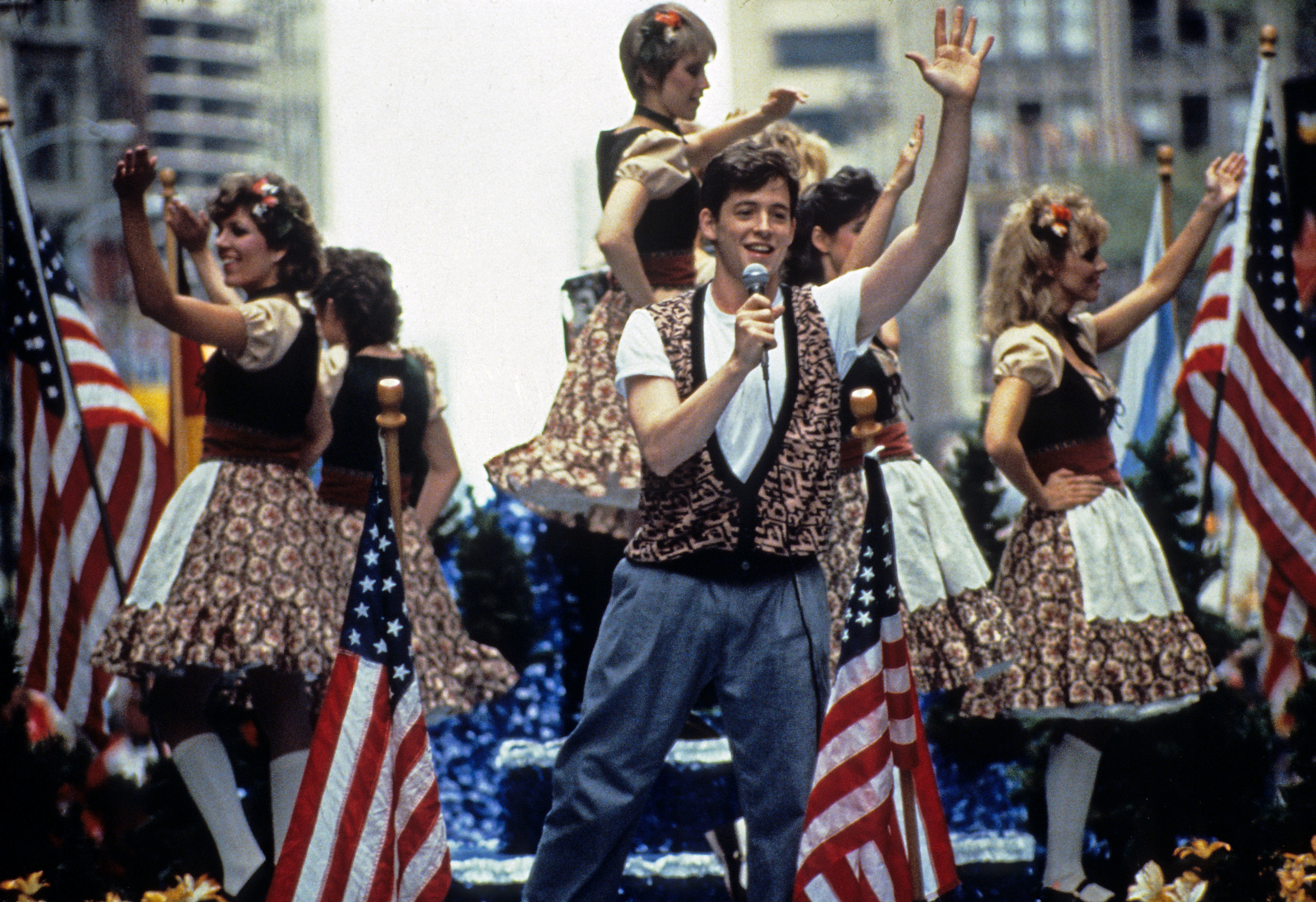 Matthew Broderick on a parade float with other people behind him in a scene from "Ferris Bueller's Day Off"
