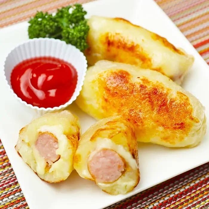 皿にのった焼きソーセージ入りジャガイモ餅とカップに入ったケチャップ。