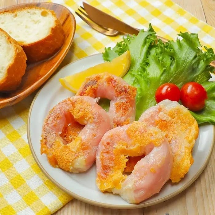 お皿に盛られたエビの天ぷらとレタス、トマト、レモンのくし切り。横にパンのスライスが見える。