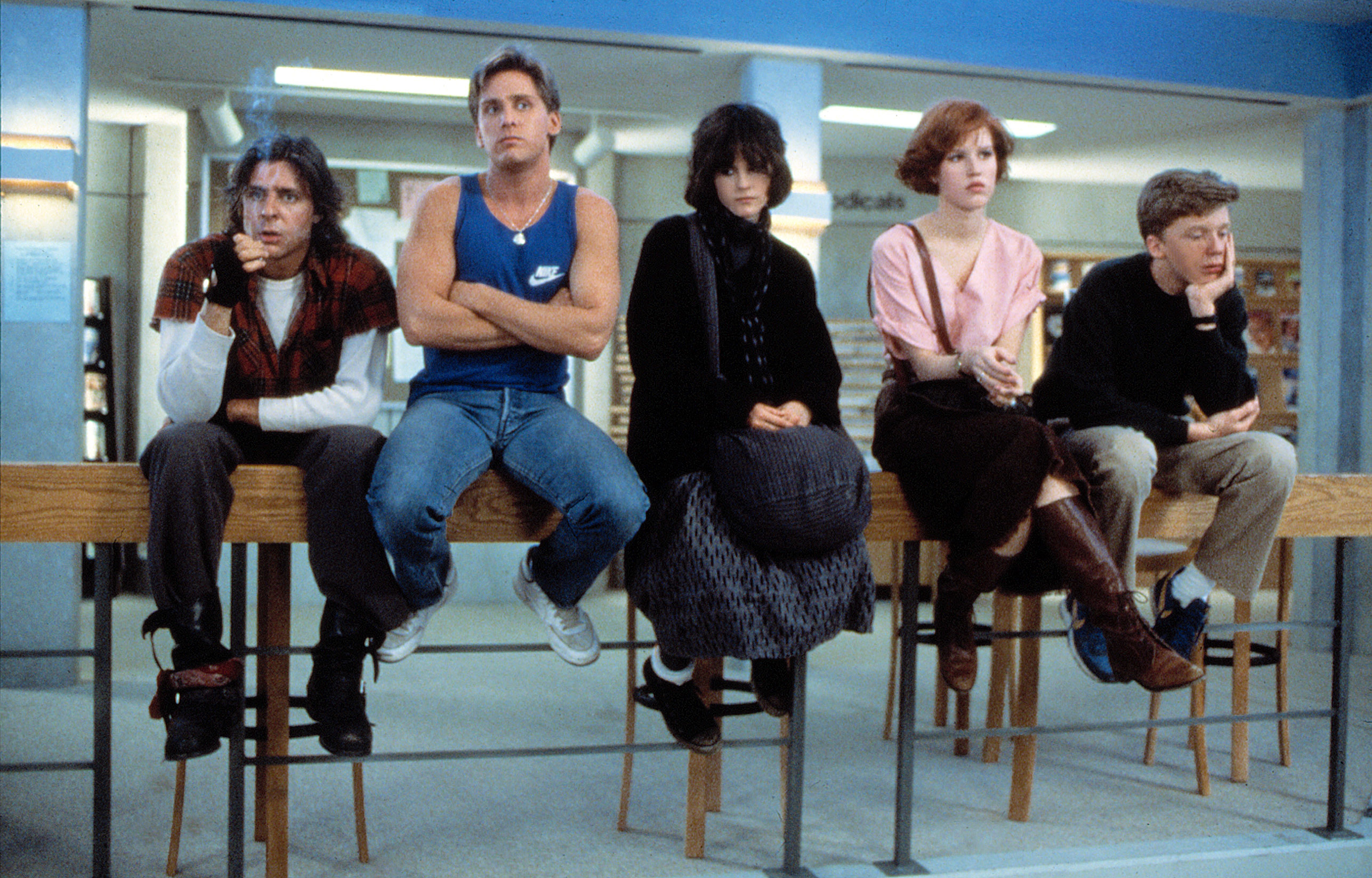 Judd Nelson, Emilio Estevez, Ally Sheedy, Molly Ringwald, and Anthony Michael Hall sitting in a library in a scene from "The Breakfast Club"