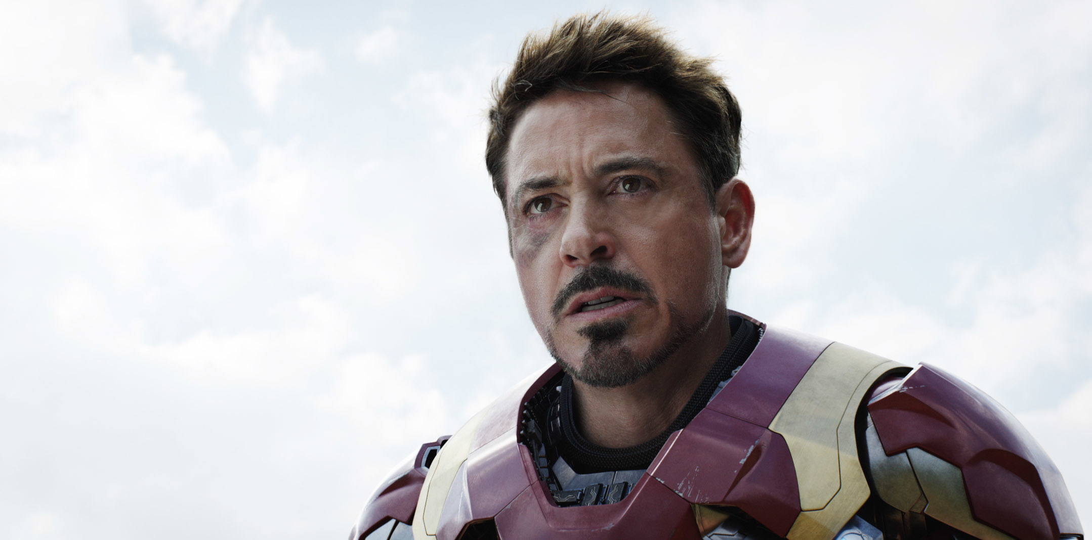 Robert Downey Jr. as Iron Man/Tony Stark looks determined, wearing his Iron Man suit in a close-up scene from a movie