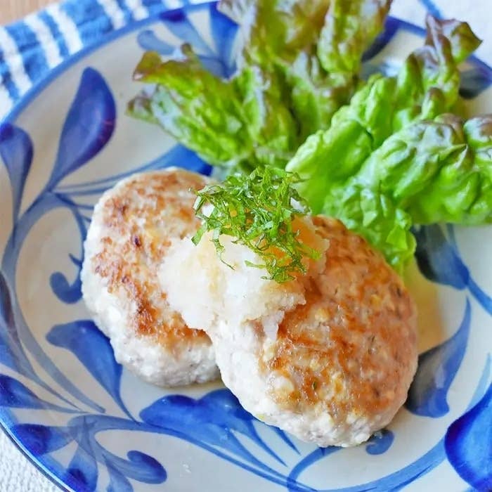 料理の写真です。皿にハンバーグが2枚載せられており、大根おろしと大葉、レタスが添えられています。