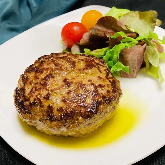 ハンバーグとサラダが白い皿の上に盛り付けられた料理。