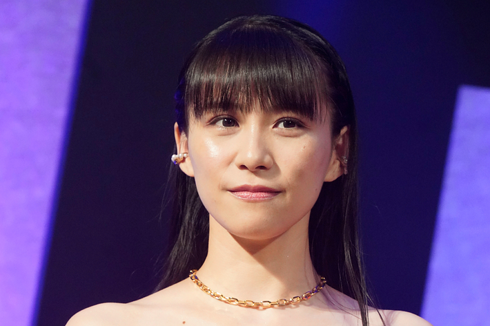 寺島しのぶが赤いオフショルダードレスを着てマイクを持っている姿。