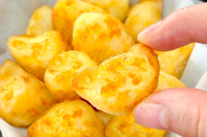 バスケットの中に入った黄金色のポテトチーズボールが手で持ち上げられている様子。