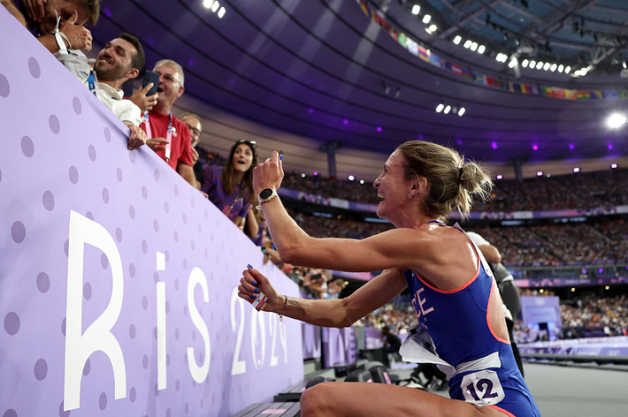 A runner is climbing into stands at a stadium. A highlighted article comment reads: “That’s embarrassing. Woman don’t do this."