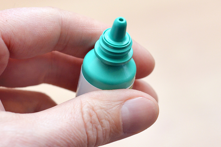 人が手に持っている点眼薬のボトル。ボトルの先端が見えています。