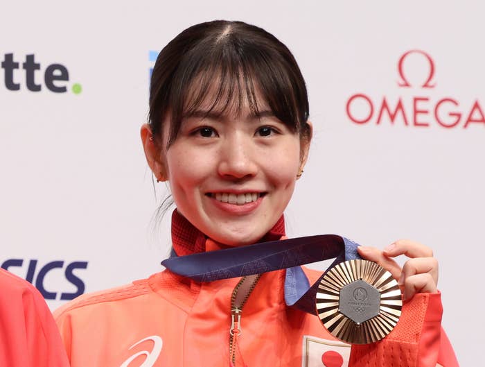 左から、日本生命のロゴが入ったユニフォームを着た女性二人が笑顔でメダルを手にしている。