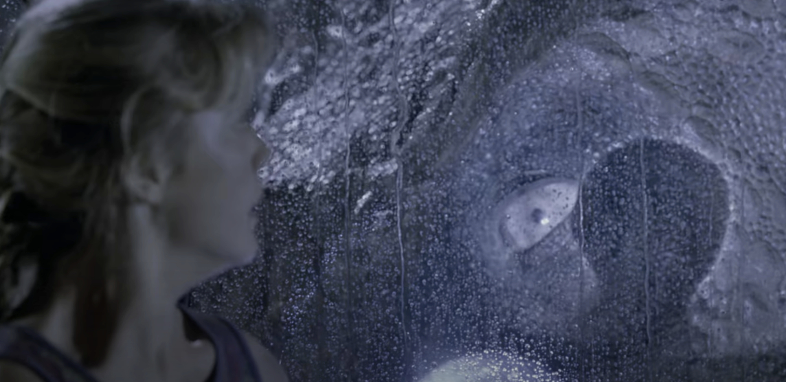 Laura Dern's character, Dr. Ellie Sattler, looks at a T. rex through a rain-soaked window in a scene from &quot;Jurassic Park.&quot;