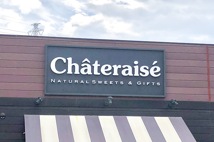 シャトレーゼの建物の外観。「Chateraise NATURAL SWEETS &amp; GIFTS」と書かれた看板が見える。