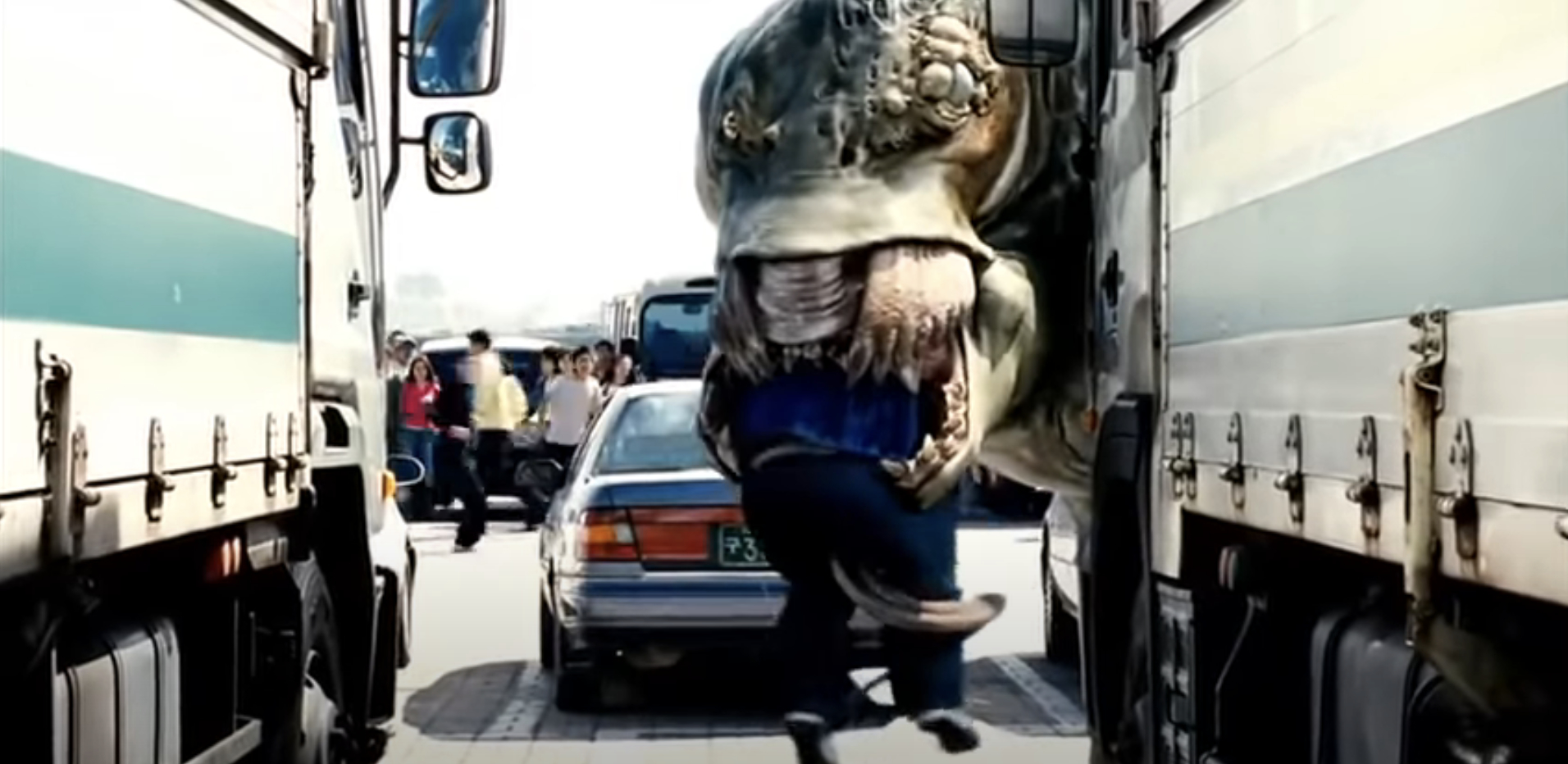 A giant creature grabs a person between two trucks in a busy street in a scene from the movie &quot;The Host&quot;