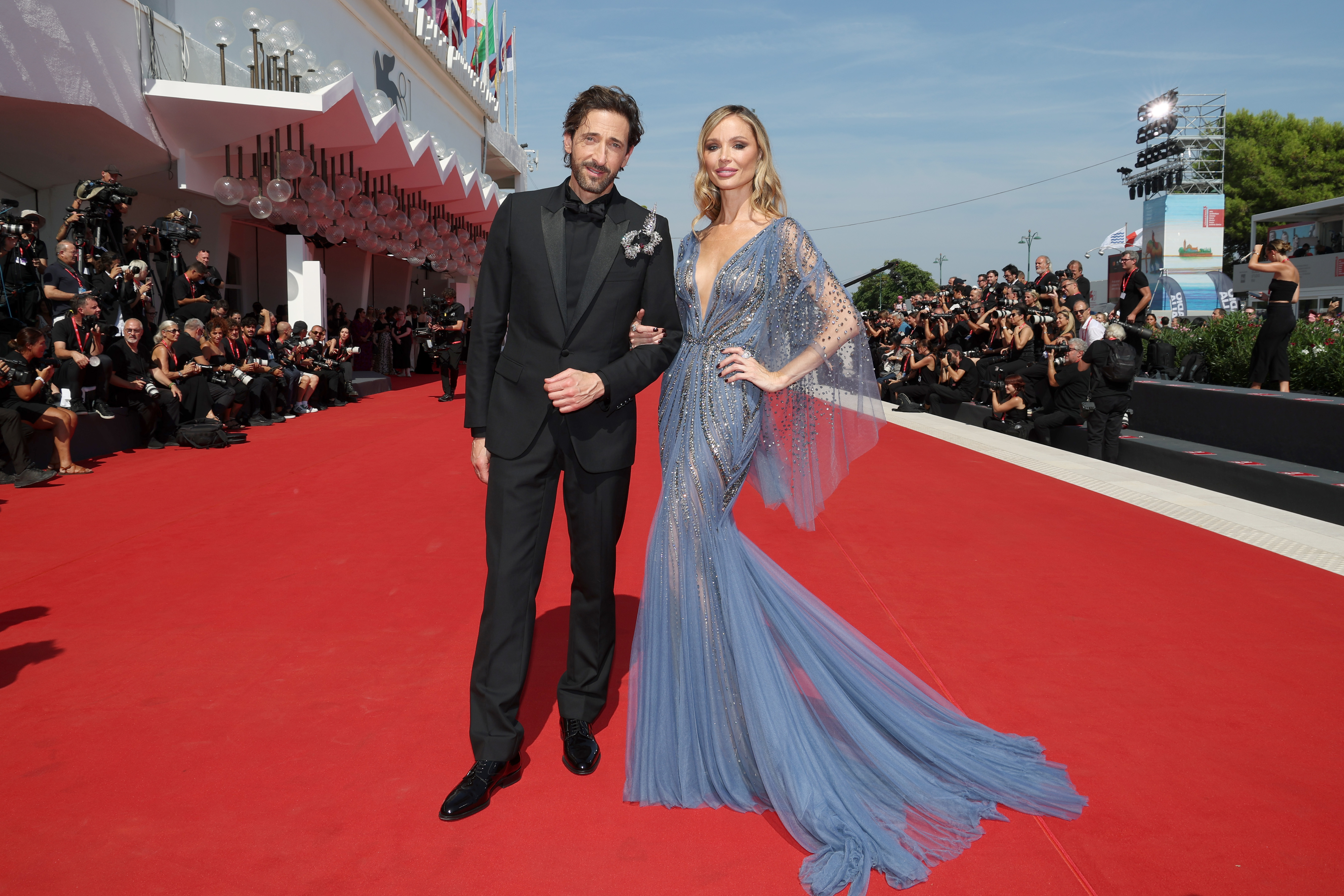 Adrien Brody and Georgina Chapman on the red carpet, Adrien in a black suit and Georgina in a flowing gown
