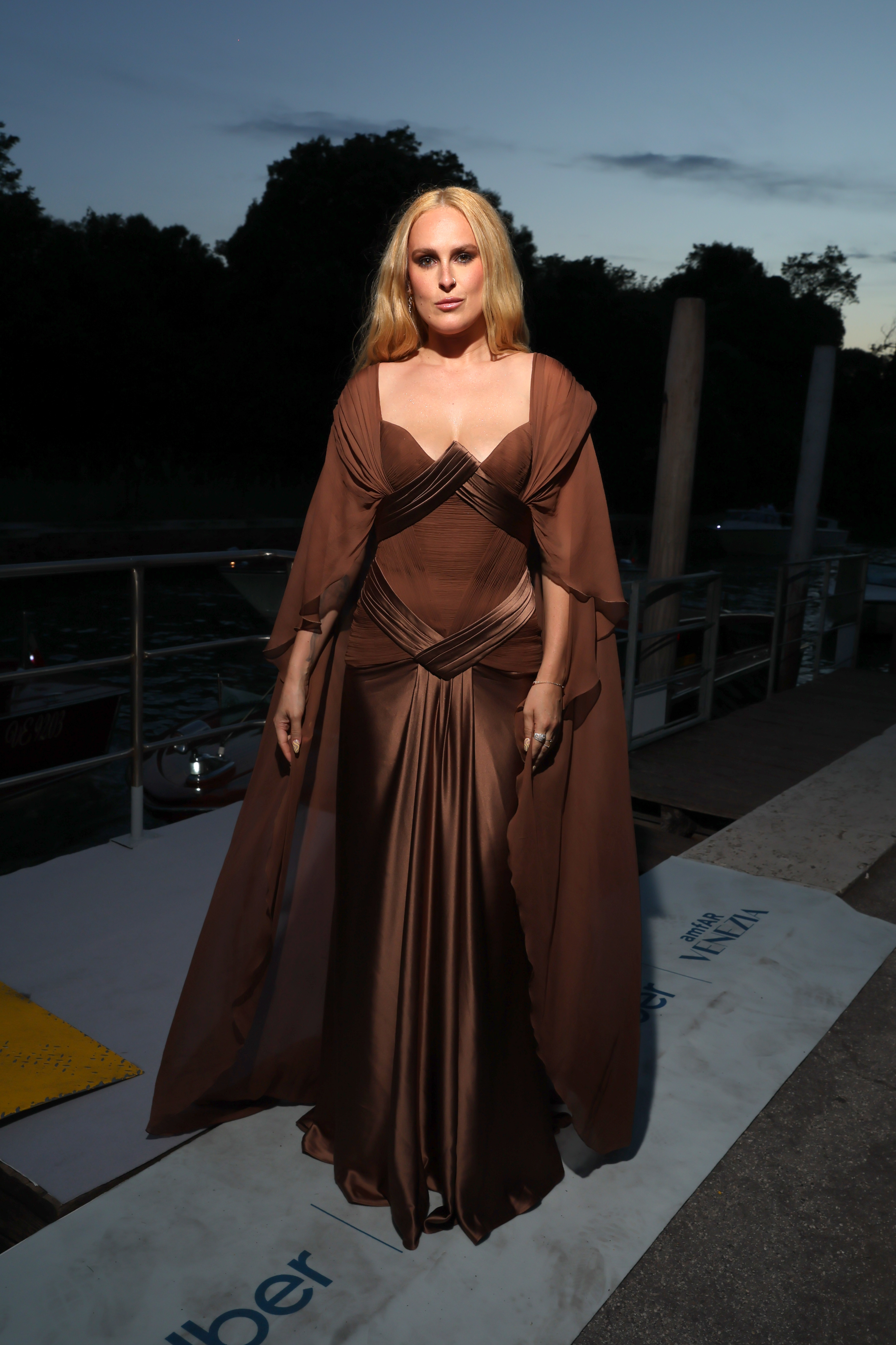 Rumer WIllis in an elegant evening gown with a cape, posing outdoors