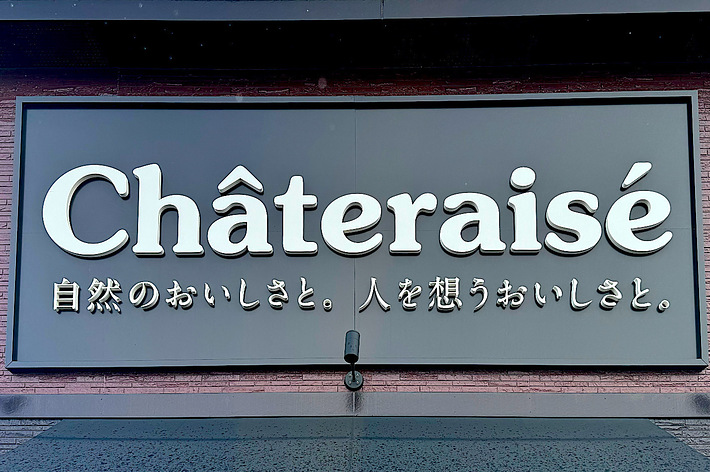 Sign for Châteraisé bakery with Japanese text below, reading “自然のおいしさと。人を想うおいしさと。”, meaning “Deliciousness of nature and thinking of people”.