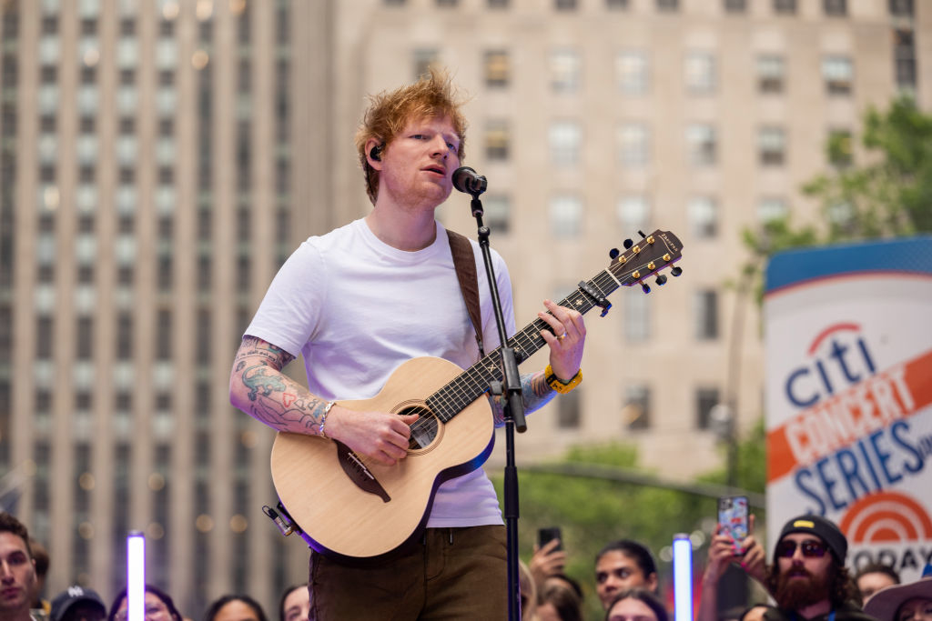 Ed Sheeran on stage wearing a t-shirt, playing guitar, and singing during a Citi Concert Series event