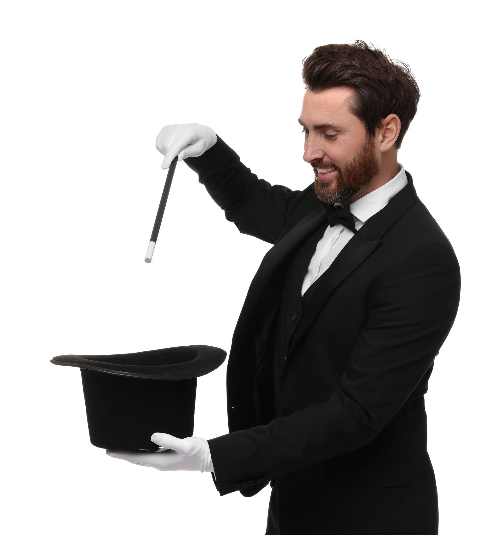 A man dressed as a magician in a formal suit, holding a wand over a top hat, performing a magic trick on a white background
