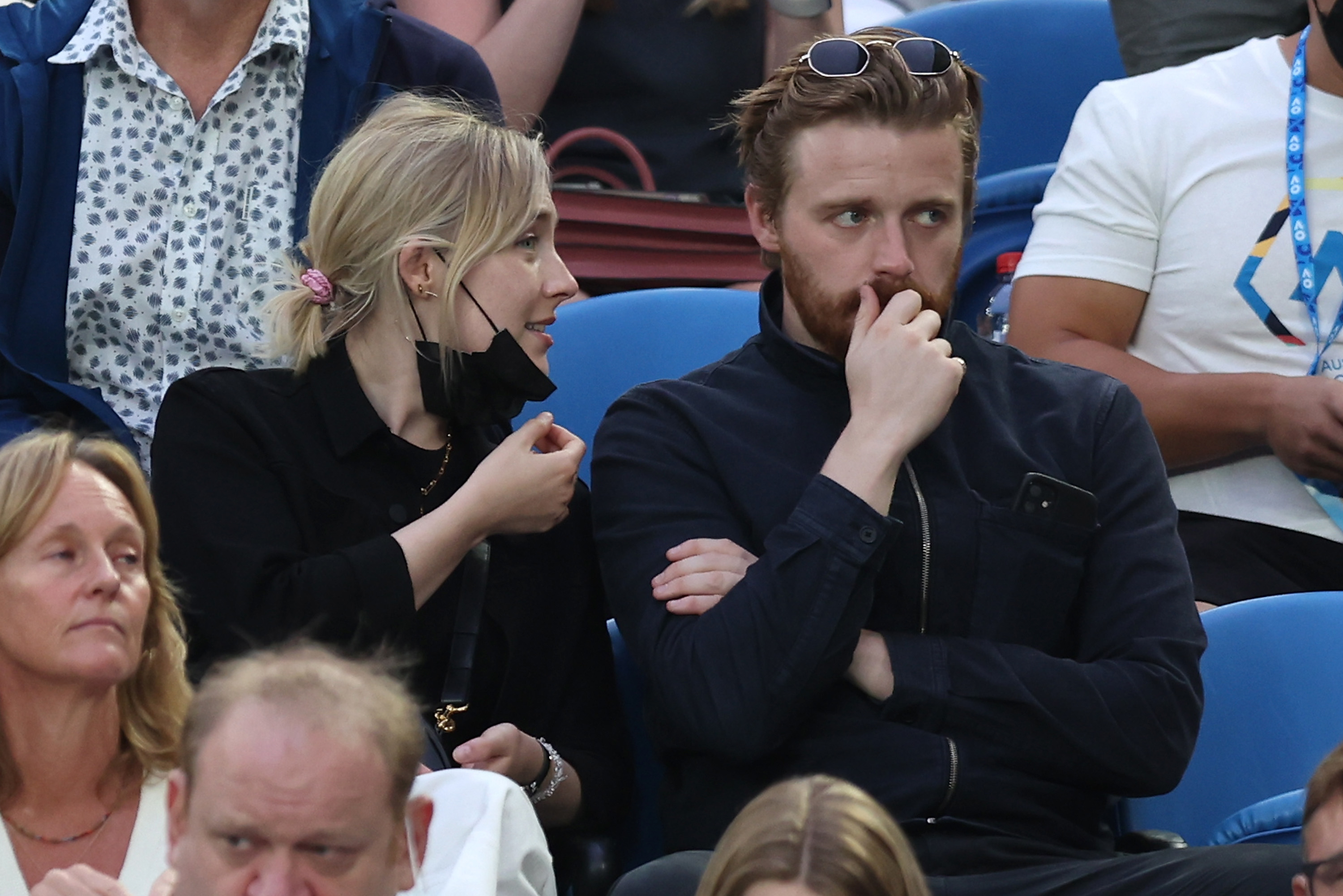 Saoirse Ronan chats with Jack Lowden in a crowd, both casually dressed. Florence has a black face mask under her chin