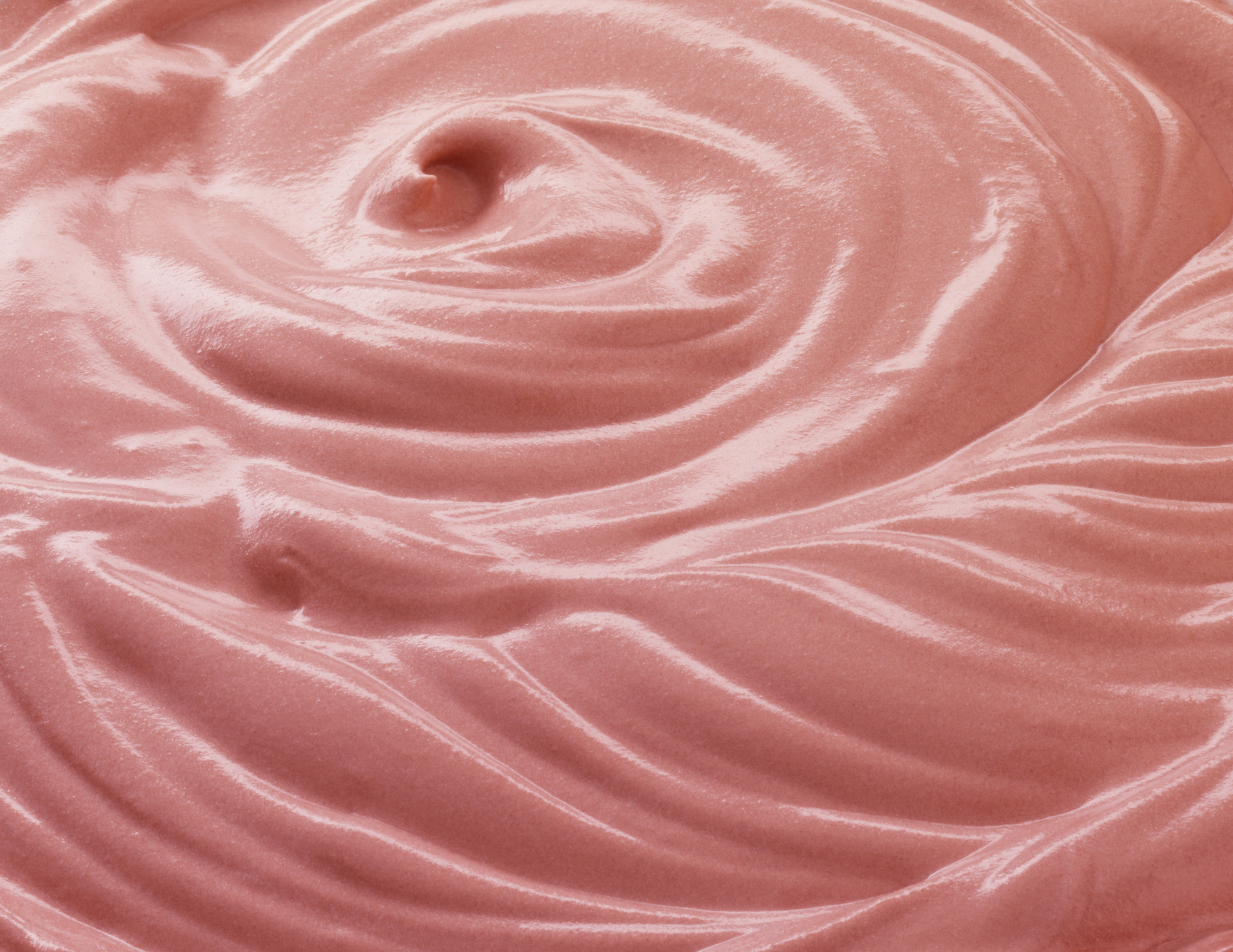 Close-up view of smooth, pink whipped texture, possibly a dessert or beauty product. No other contextual elements are present
