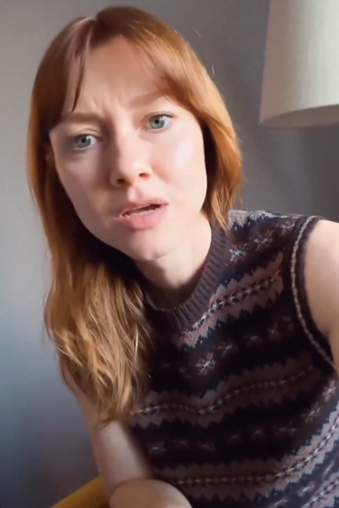 Valorie Curry looking directly at the camera with a curious expression, wearing a patterned sleeveless sweater