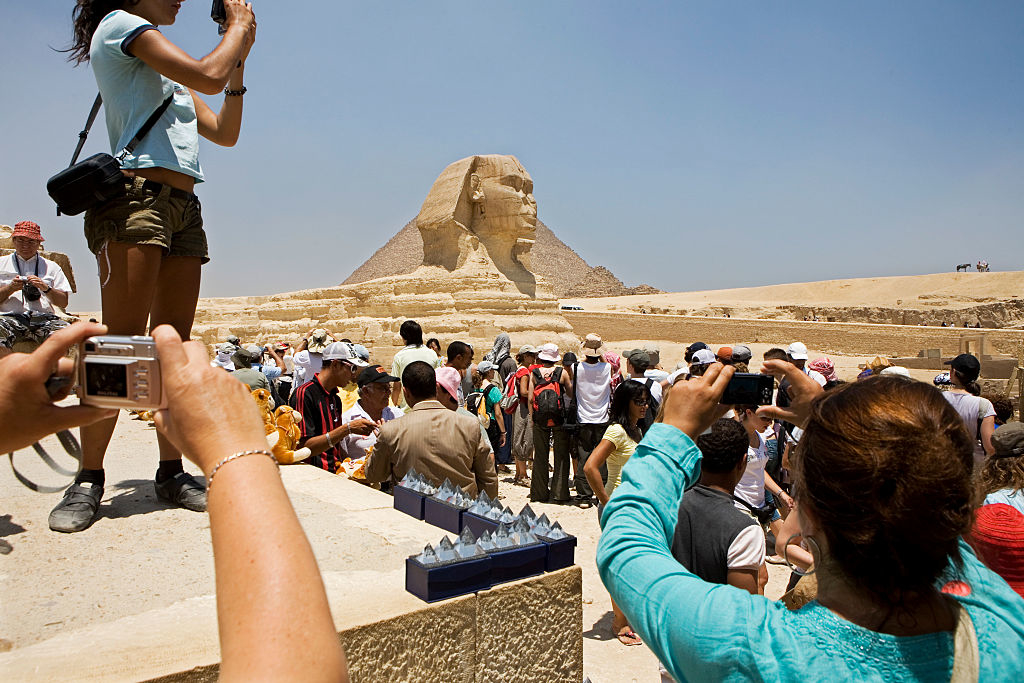 Tourists gather around the Great Sphinx of Giza, taking photos and enjoying the historic site