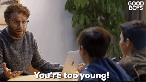 Seth Rogen sits at a table with two boys, talking. Text on the image reads "You're too young!" Above in the corner, it says "Good Boys."