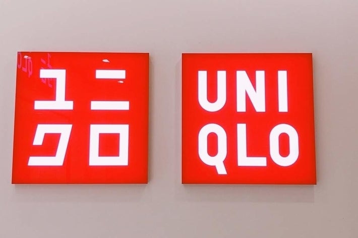 Two red square signs with white text. The left sign has Japanese characters; the right sign reads &ldquo;UNIQLO&rdquo;