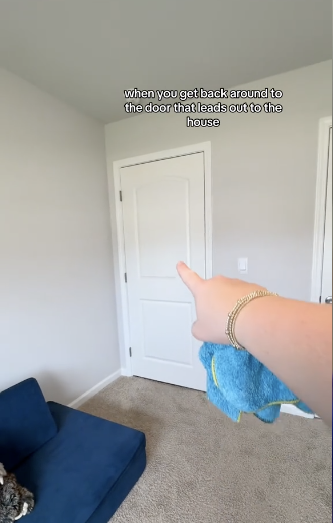 A hand holding a blue cloth points to a door