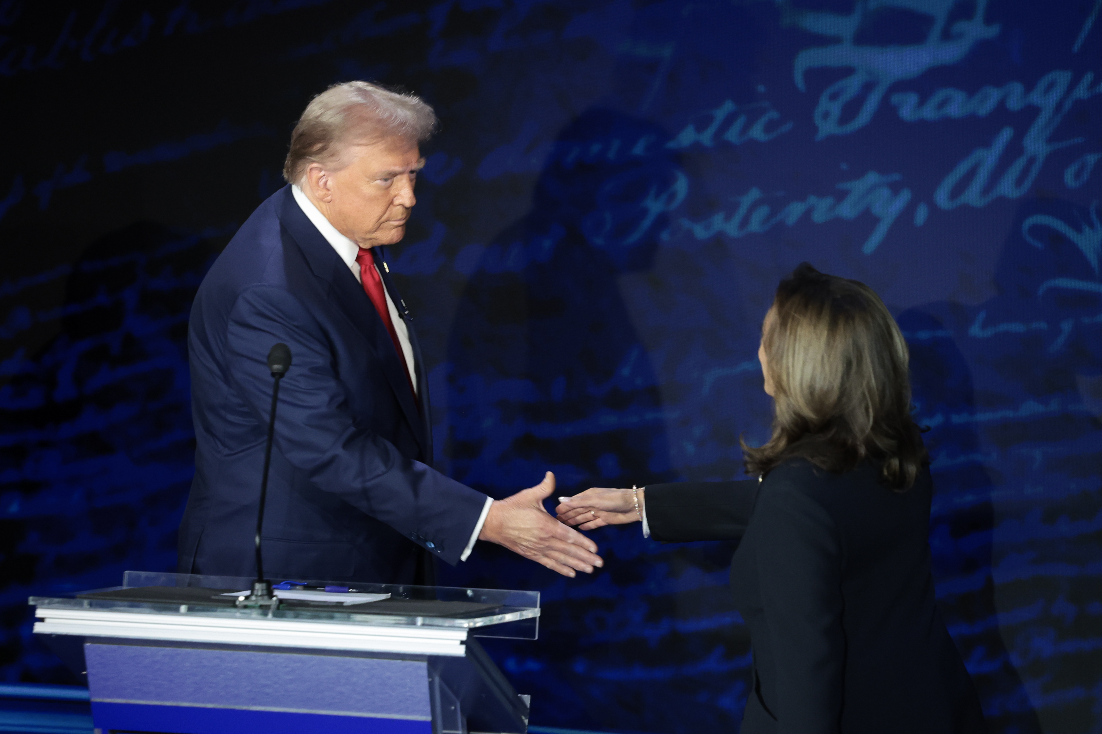 Donald Trump and Kamala Harris shake hands on stage during a formal event