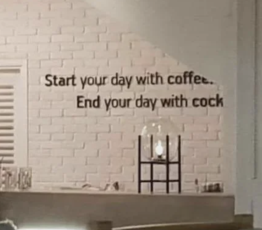 A wall sign in a café reads, "Start your day with coffee. End your day with cock." There's a lamp and some objects below the sign