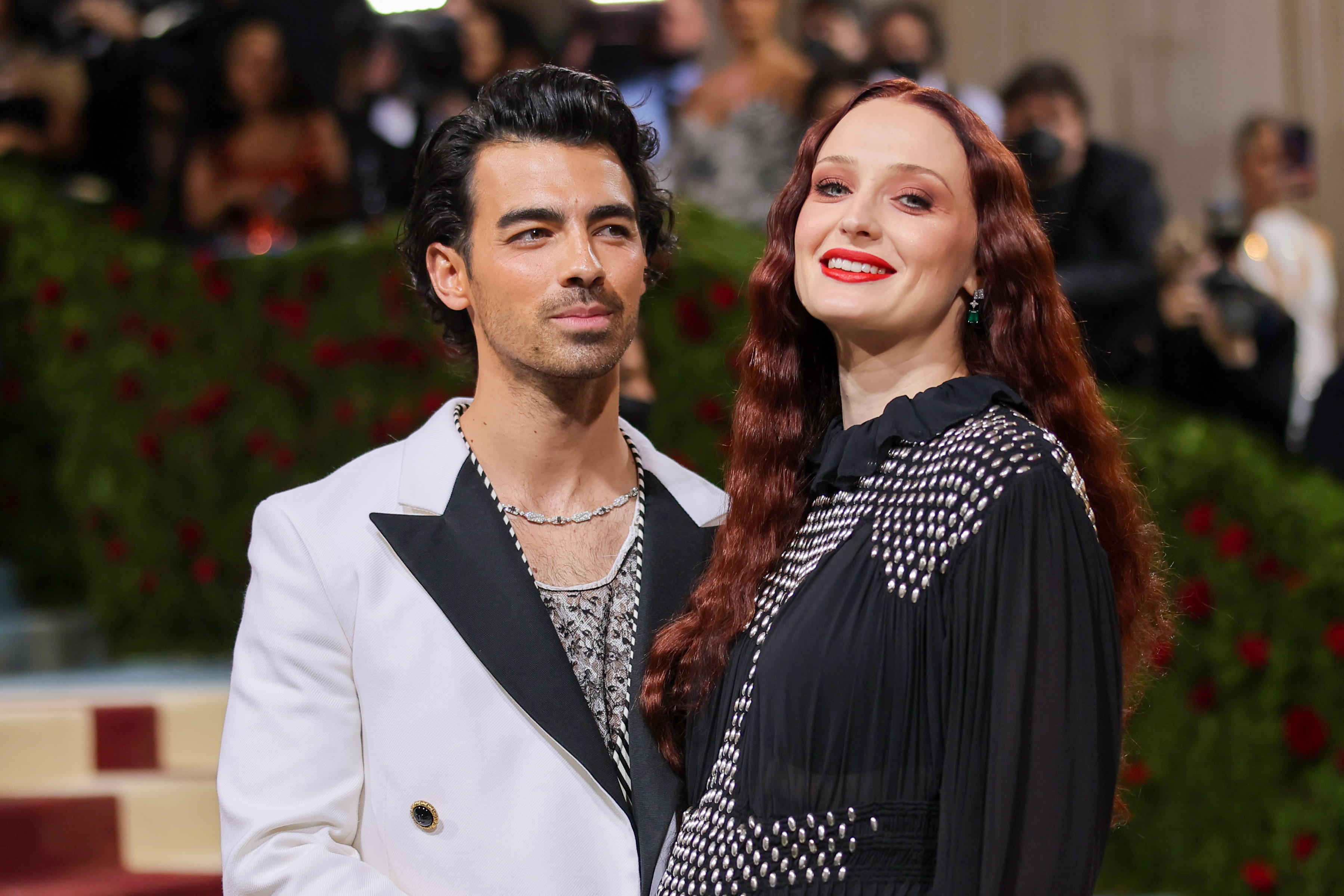 Joe Jonas and Sophie Turner smile while posing on a red carpet