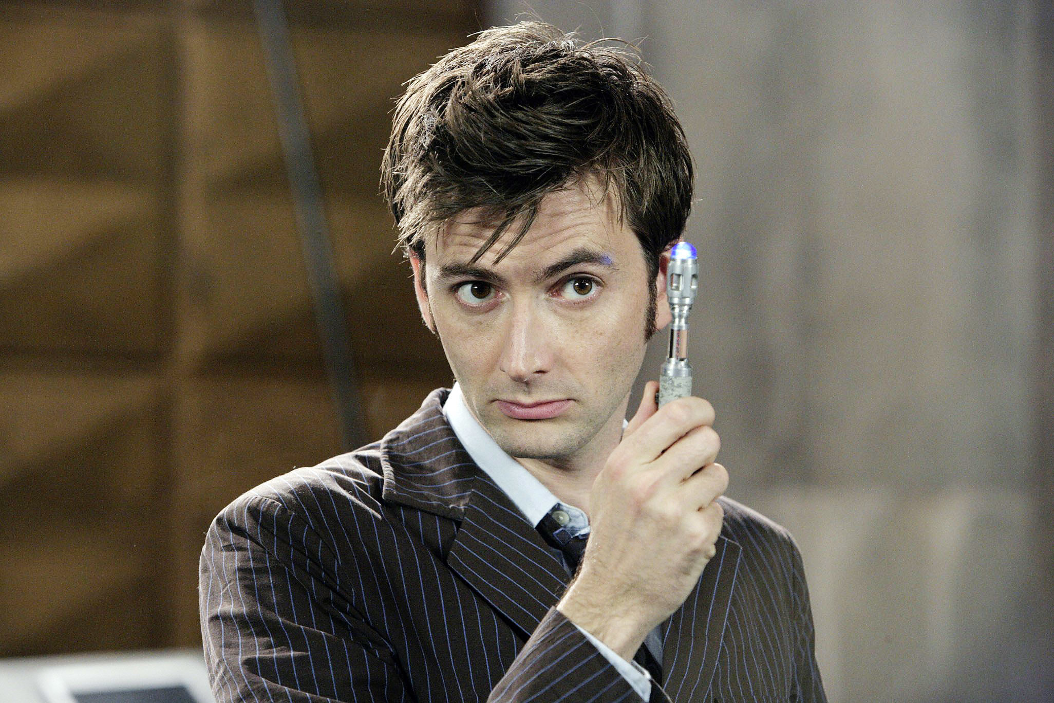David Tennant, wearing a pinstripe suit, holds up a sonic screwdriver in a scene from "Doctor Who."