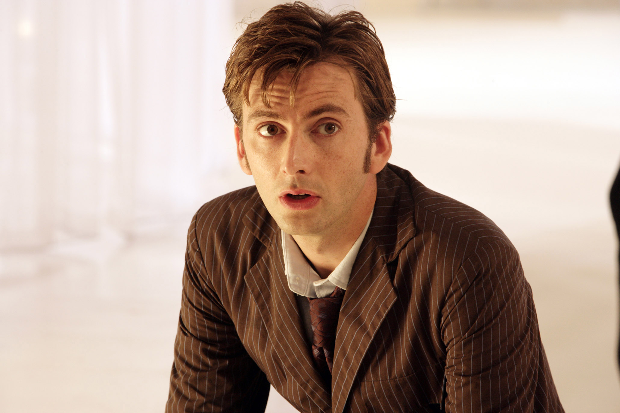 David Tennant in a pinstripe suit, looking surprised or concerned