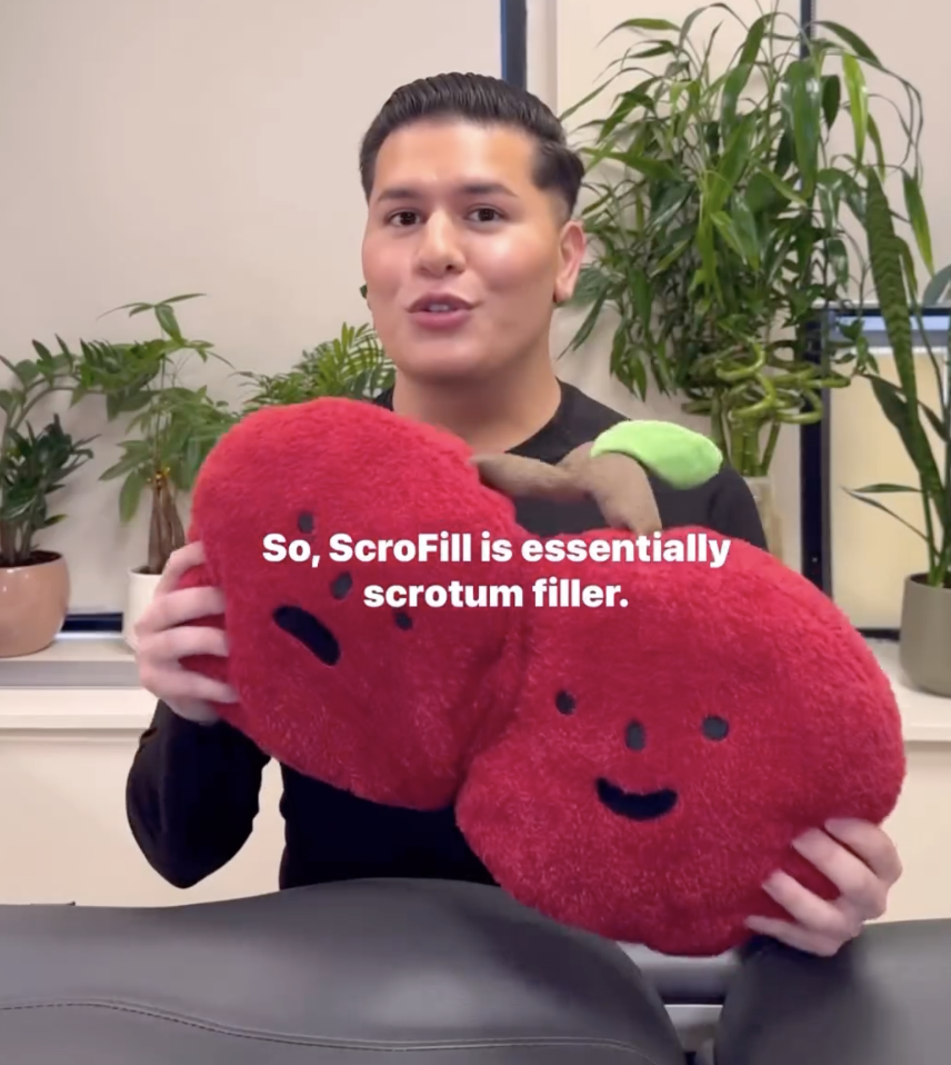 Chris holding two red plush cherries with faces, to signify someone's scrotum, with text above that reads, "So, ScroFill is essentially scrotum filler"