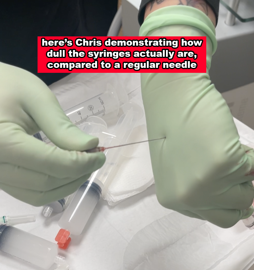Chris demonstrating the dullness of a syringe compared to a regular needle while wearing green gloves and lightly pressing the syringe into his hand