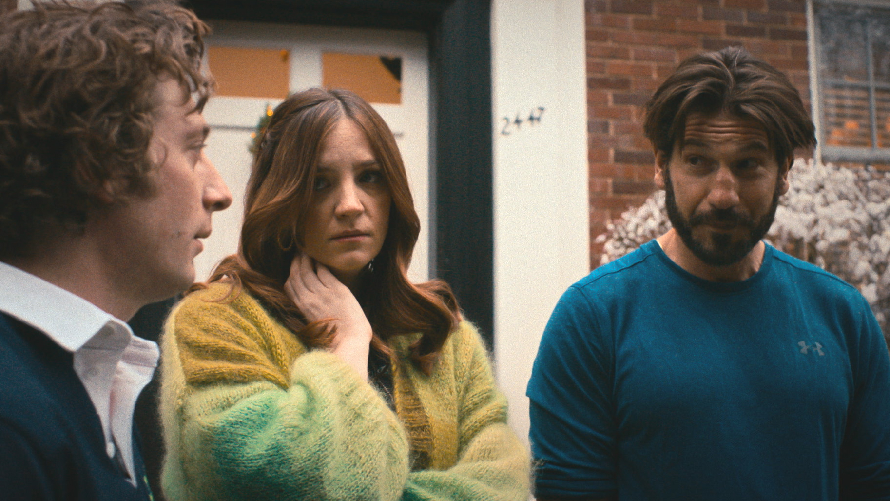 Jeremy Allen White, Abby Elliot, and Jon Bernthal stand in front of a door, engaged in conversation in a scene from &quot;The Bear&quot;